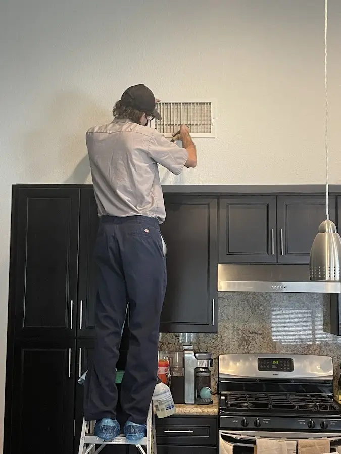 Technician inspecting an air vent during HVAC service in Anna